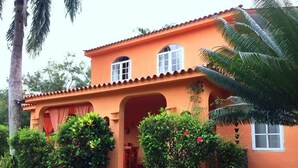 A two-story building with a terracotta facade, arched doorways, and a stone pathway leading to the entrance. - Madrugada Residencial (Las Terrenas)