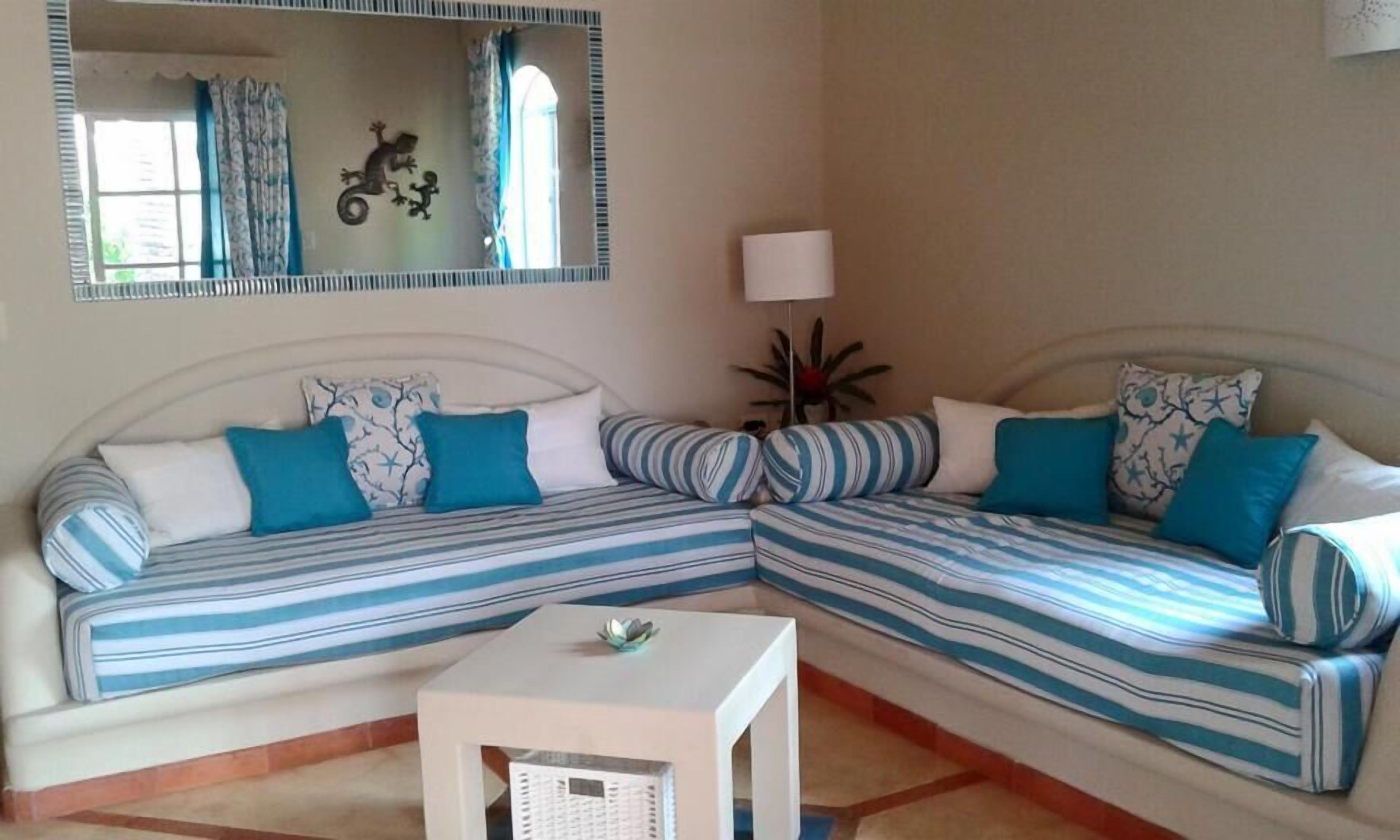 Una habitación con dos sofás a rayas, una pequeña mesa blanca y un espejo en la pared.