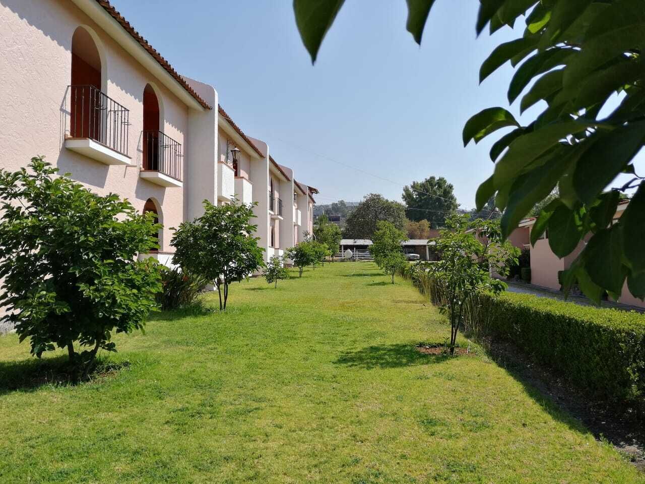 Un patio con un edificio que presenta ventanas de arco y balcones, rodeado de césped cuidado y árboles pequeños.