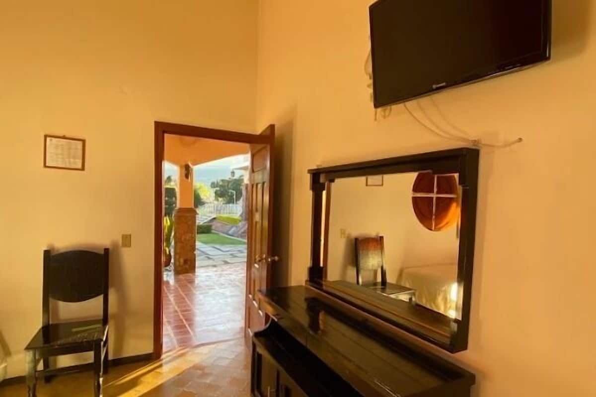 Uma sala de estar com televisão de tela plana na parede, um piano e uma poltrona.