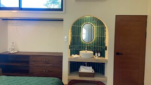 Een hotelkamer met een bed, een kaptafel met spiegel, een wastafel en een deur.