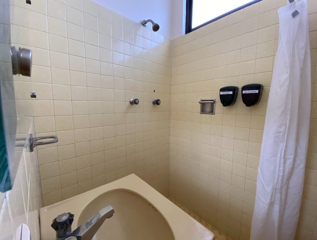 A bathroom with a bathtub, a shower, and two hand dryers.