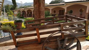 A wooden bench with a large wheel, set against a backdrop of a building with arched windows and a tiled roof.