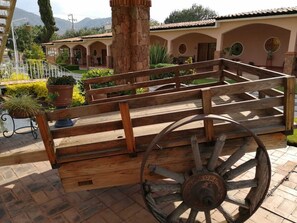 A wooden bench with a large wheel, set against a backdrop of a building with arched windows and a tiled roof. - Hotel Ojo de Agua (Ciudad Hidalgo)