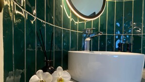 A bathroom with a white sink, a mirror, and green tiled walls.