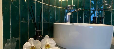 A bathroom with a white sink, a mirror, and green tiled walls.