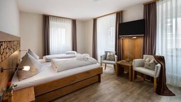 Ein modernes Hotelzimmer mit einem großen Bett, einem Schreibtisch, einem Sessel und einem Fernseher.