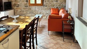 Una stanza con pareti in pietra, un tavolo da pranzo, sedie, un divano e una TV.