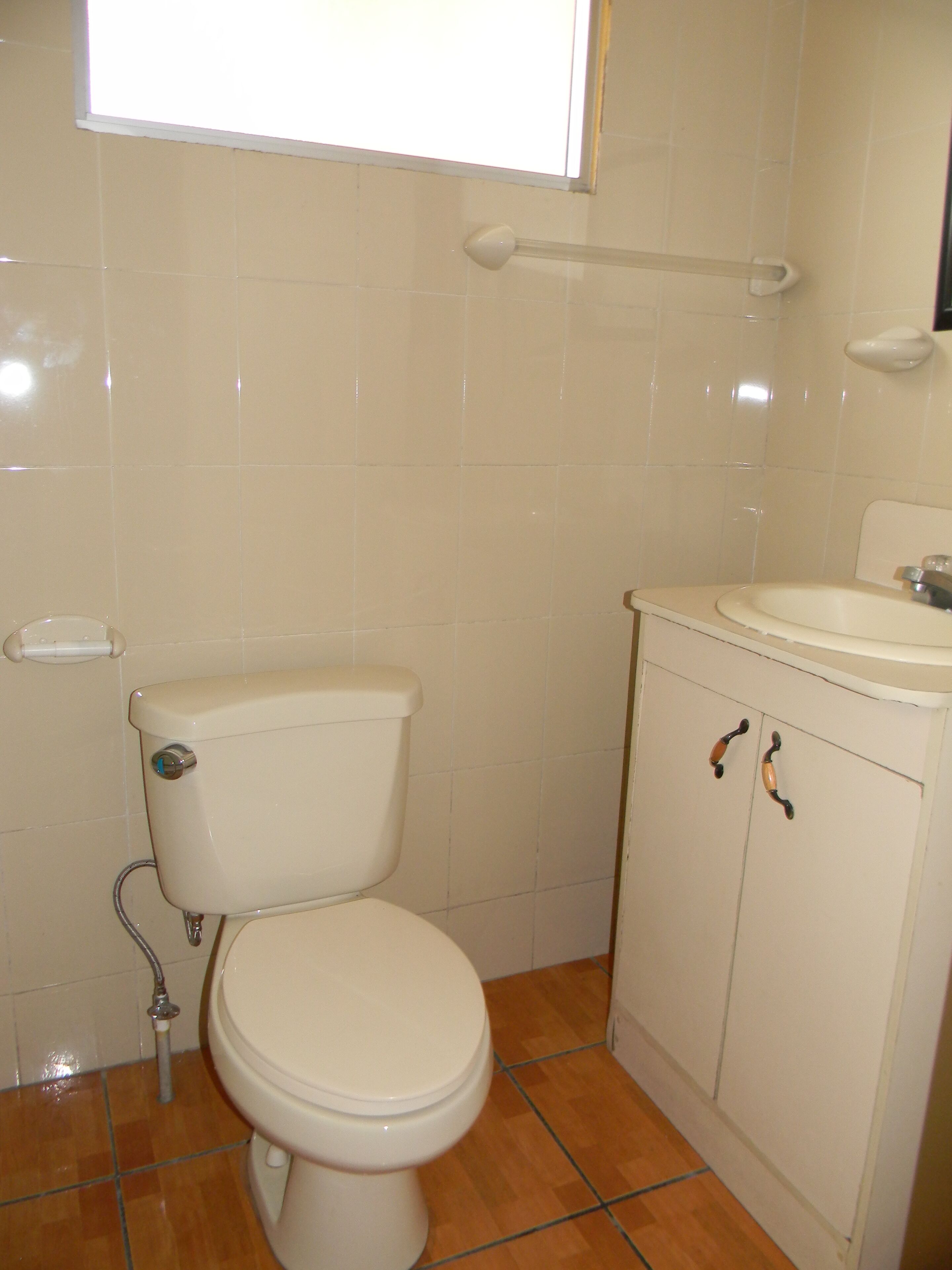 A bathroom with a toilet, sink, and tiled walls.