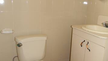 A bathroom with a toilet, sink, and tiled walls.
