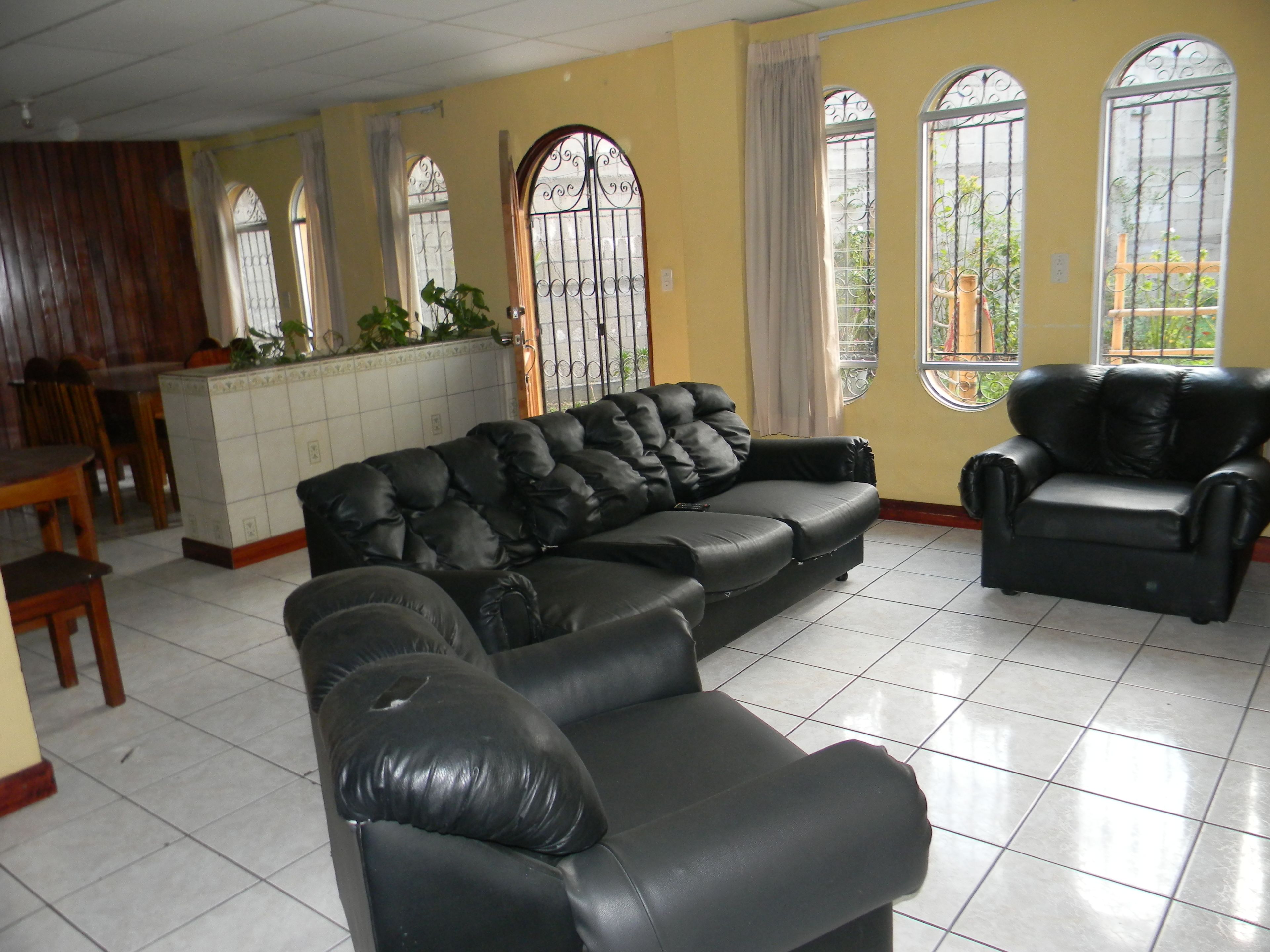 Una sala de estar con un sofá modular, un sillón aparte y un comedor con mesa y sillas de madera.