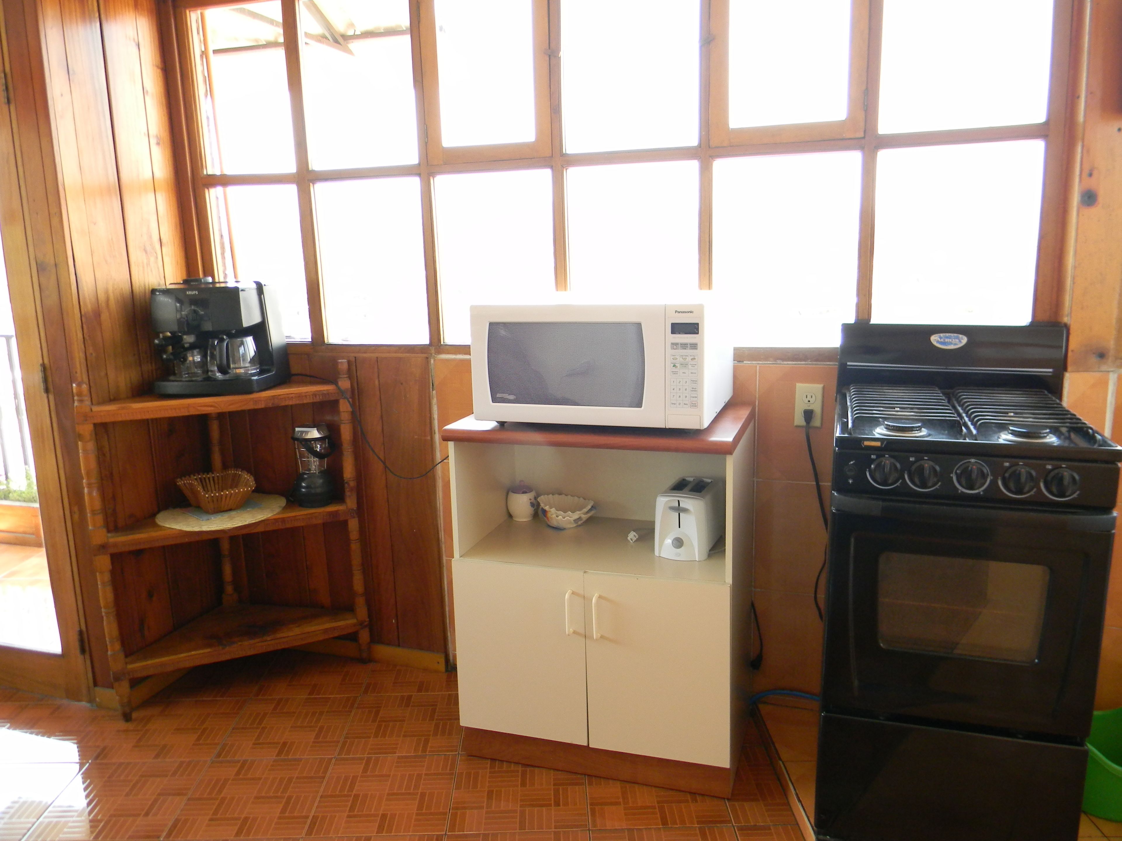 A compact kitchen with a microwave, toaster, coffee maker, and a stove.