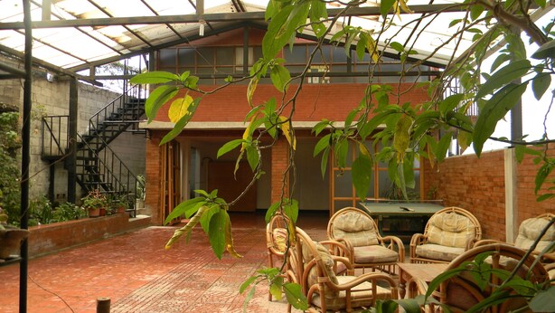 Un espace patio intérieur doté d’un sol en briques, de meubles en osier et de plantes en pot.