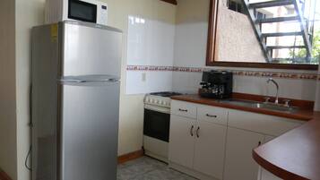 Une cuisine compacte équipée d’un réfrigérateur, d’une cuisinière et d’une machine à café.