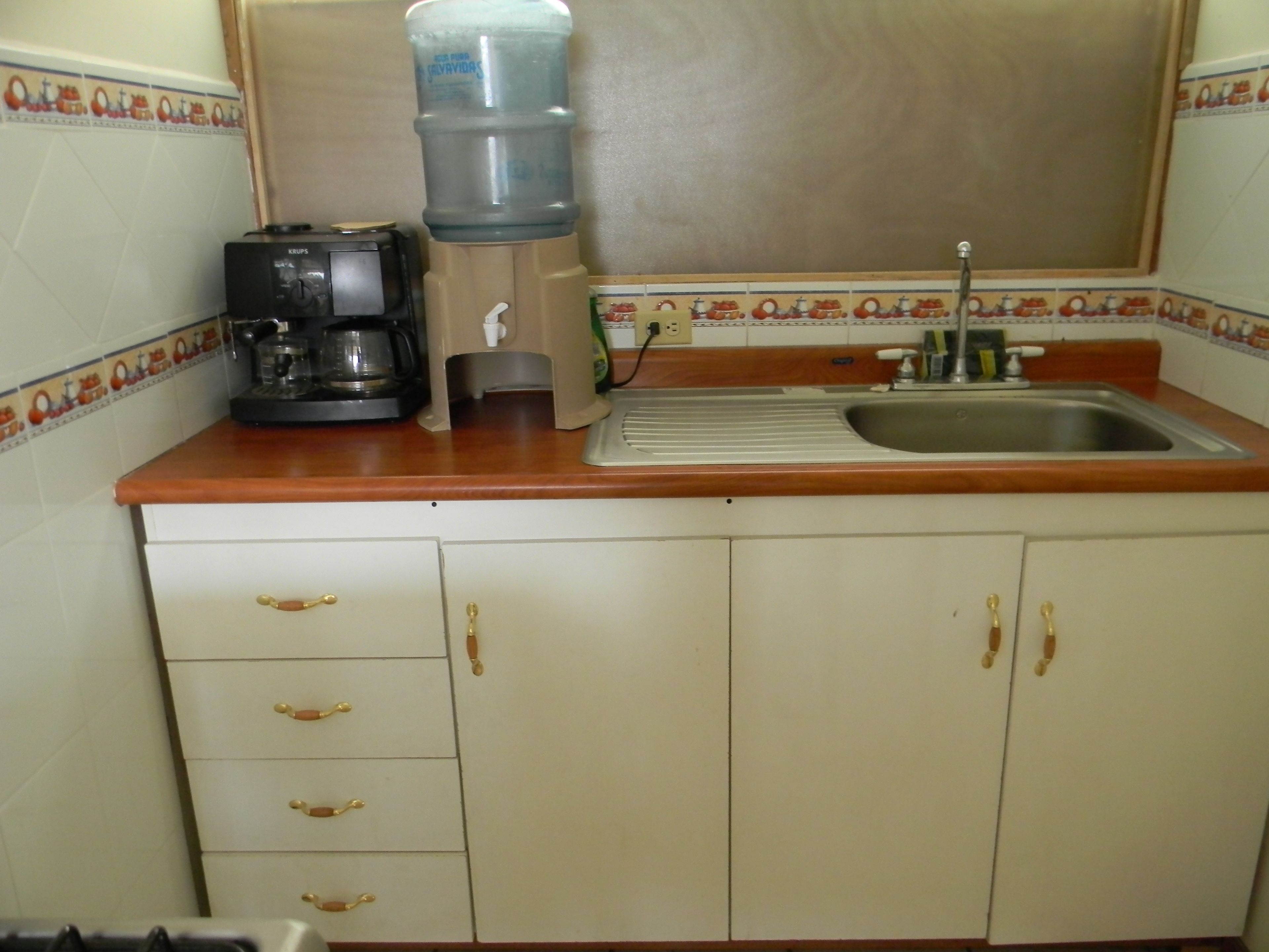 A kitchen with a coffee maker, a water dispenser, and a sink.
