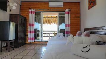 Quarto de hotel com cama, escrivaninha, armário e varanda com cortinas.