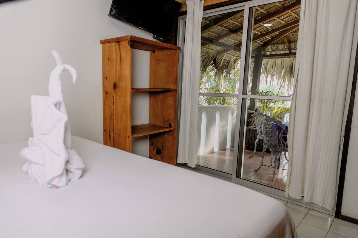 Habitación de hotel con cama, estante de madera y vistas al exterior.