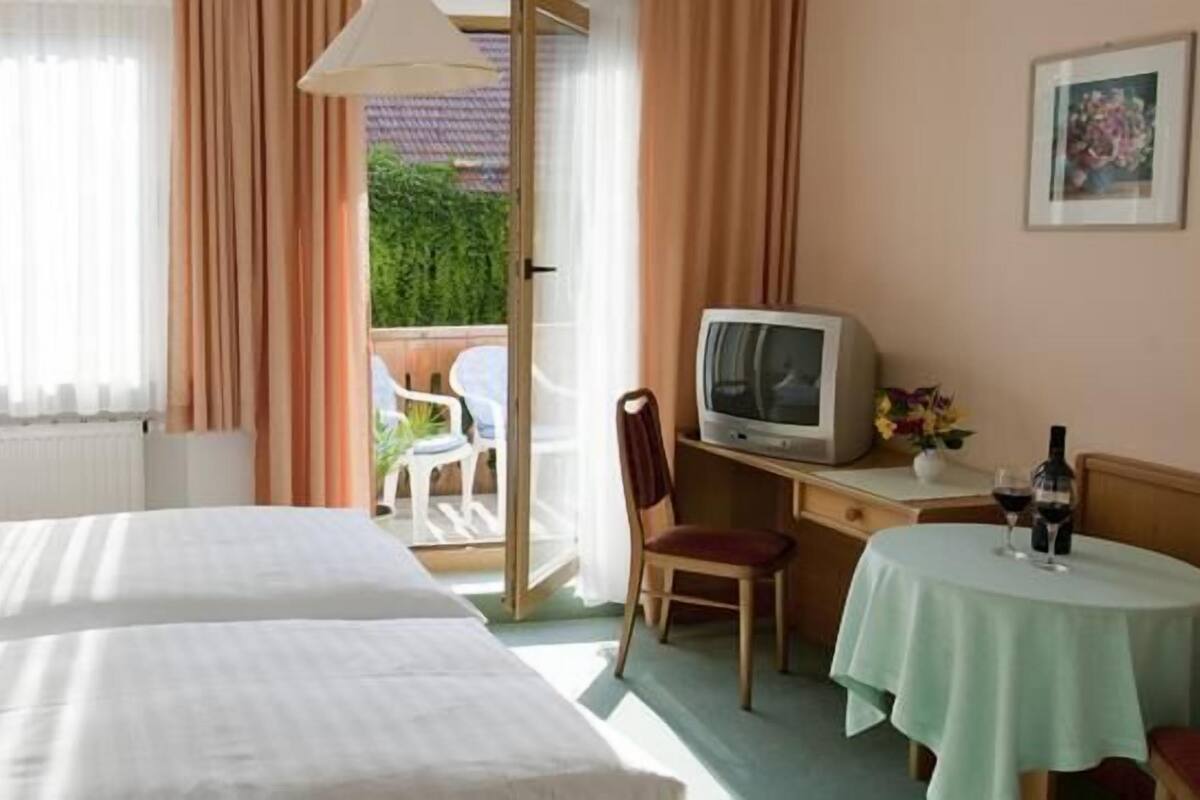 Habitació d'hotel amb dos llits, un escriptori amb televisió, una petita taula amb begudes i vistes a l'exterior.
