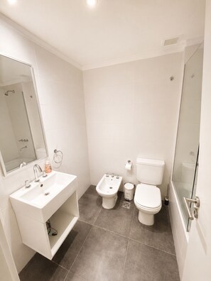 Een moderne badkamer met een wastafel, toilet, douchecabine en een bidet.