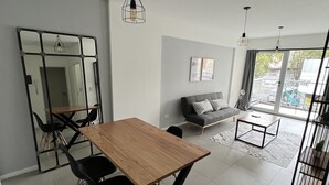 Ett modernt vardagsrum med en matplats, med ett träbord, svarta stolar, en soffa och en stor spegel.
