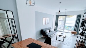 Ett modernt vardagsrum med matplats, soffa och en balkong med utsikt.