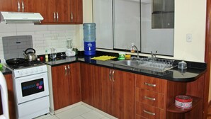 Una cocina con armarios de madera, una estufa blanca, un lavamanos y un dispensador grande de agua.