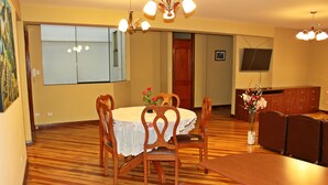 Un comedor con mesa de madera, sillas y un jarrón de flores.