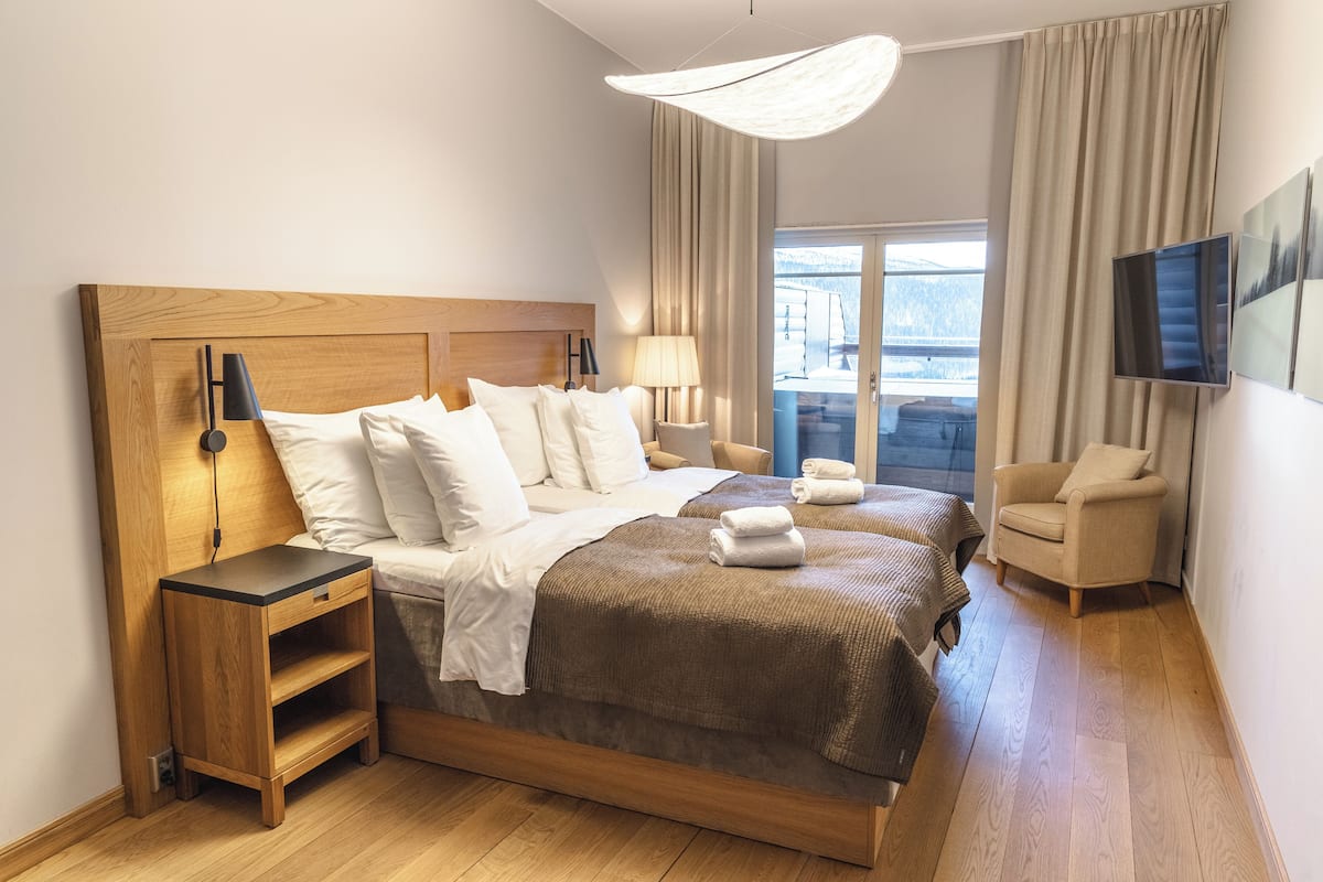 Une chambre d’hôtel avec un grand lit, une table de chevet, une chaise, un téléviseur et une vue sur l’extérieur.