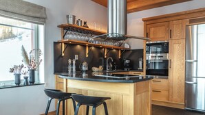 Una cocina moderna con una isla central, electrodomésticos de acero inoxidable, armarios de madera y un ventanal con vistas.