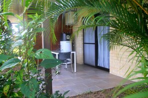 A patio area with a table and chairs, a water heater, and a brick wall. - Eden Appartel Koné (Kone)