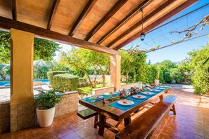 An outdoor dining area with a wooden table set for four, surrounded by stone walls and potted plants. - Country style Finca Can Verga Pollensa with pool (Pollensa)