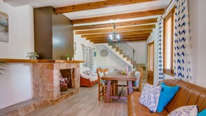 A cozy living room with a stone fireplace, wooden beams, a dining area, and a staircase leading to another level. - Country style Finca Can Verga Pollensa with pool (Pollensa)