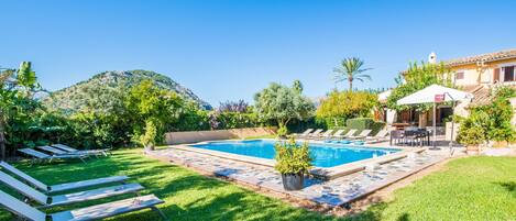 A swimming pool surrounded by a well-maintained lawn, with lounge chairs and a patio area.