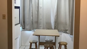 A small room with a window, a table with four stools, and a sign on the wall. - Lagoa Apartments (Florianópolis)