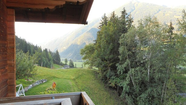Een houten hutje met een balkon met uitzicht op een bergachtig landschap.