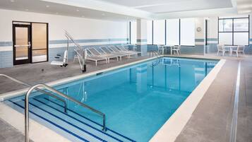 Ein Swimmingpool mit klarem, blauem Wasser, umgeben von Liegestühlen und einem gefliesten Boden.