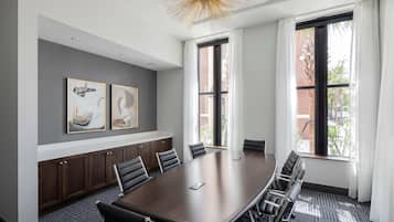 A conference room with a large table, chairs, and artwork on the wall.