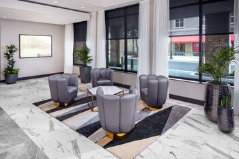 A spacious living area with a blue sofa set, a glass railing, and a modern kitchen in the background. at Hyatt Place Mount Pleasant Towne Centre
