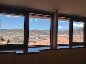 Una habitación con un amplio ventanal que da a una vista panorámica de la ciudad y montañas.