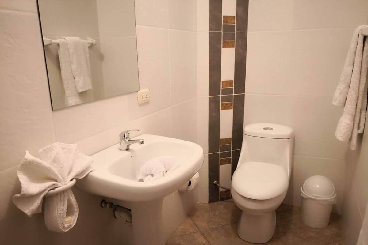 Un baño con lavamanos, inodoro y espejo.