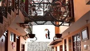 A spacious courtyard with a tiled floor, a wooden bench, and a hanging chair. - Kuska Guest House (Cusco)