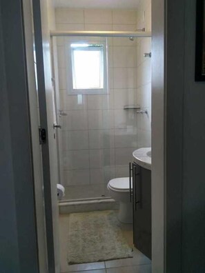 A small, enclosed bathroom with a toilet, a sink, and a shower area. - Recanto Hermosa (Xangri-La)