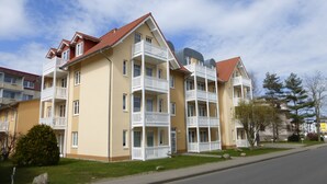 A multi-story residential building with balconies, a red-tiled roof, and a yellow facade. - Central, 300m from the beach, Apartment Strandschlösschen II, family-friendly (Kühlungsborn)