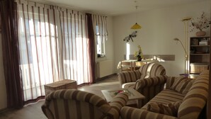 A living room with striped sofas, a dining table, and a yellow pendant light. - Central, 300m from the beach, Apartment Strandschlösschen II, family-friendly (Kühlungsborn)