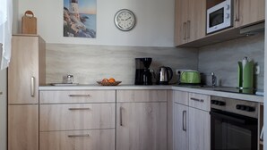 A kitchen with wooden cabinets, a microwave, a coffee maker, and a toaster. - Central, 300m from the beach, Apartment Strandschlösschen II, family-friendly (Kühlungsborn)