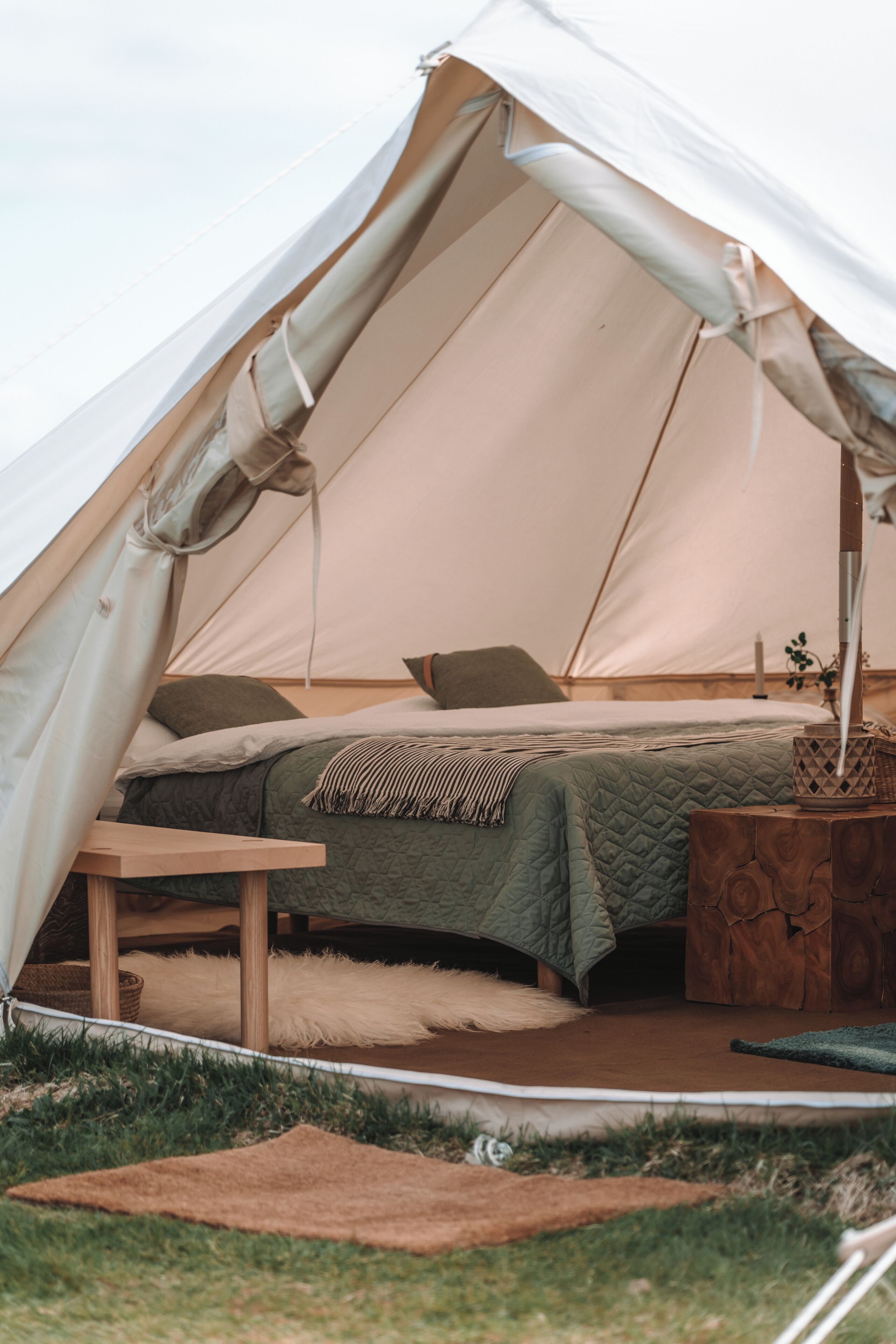 Ein Zelt mit einem Bett, einem Tisch und einem Holznachttisch.