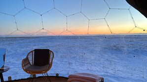 Una tenda amb un llit, una cadira i vista al mar.