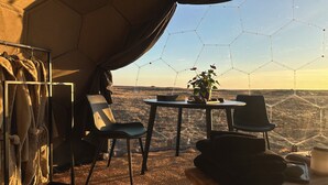 Una tenda amb taula i cadires, una estant penjant i vista del paisatge.