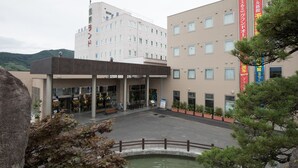 A hotel with a modern facade, a covered entrance, and a small pond in the foreground. - Kur and Hotel Isawa (Fuefuki)