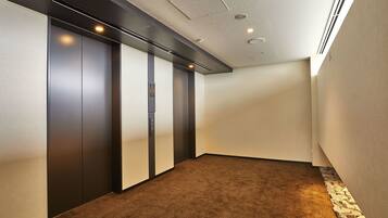 A modern elevator with a control panel, a carpeted floor, and a stone accent wall.